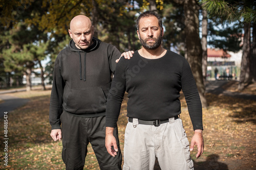 Foto Two moody and frowning bully hooligan thugs in public park