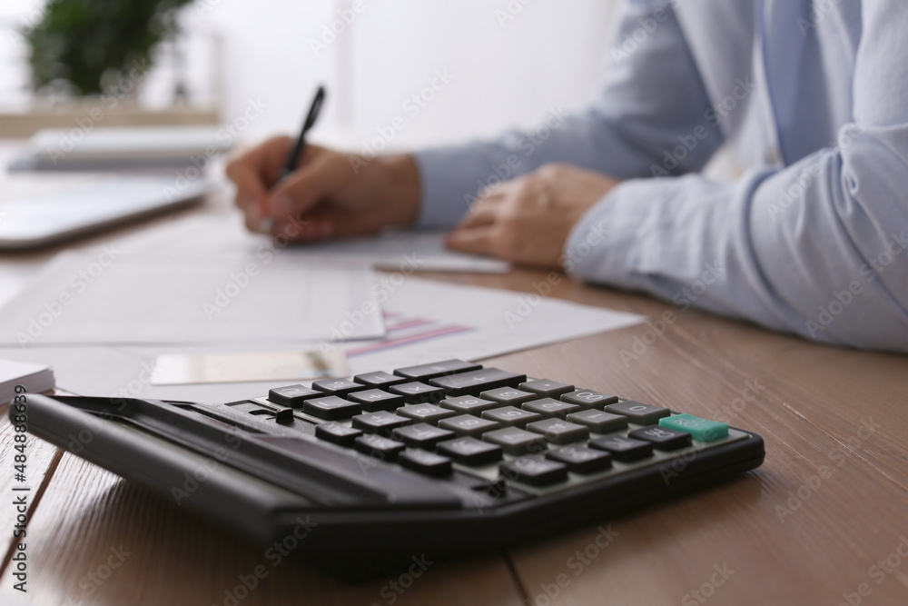 Tax accountant working in office, focus on calculator Tax accountant working in office, focus on calculator