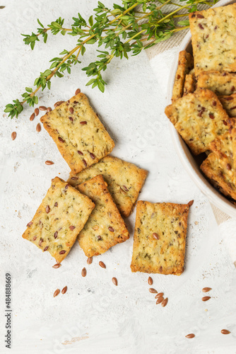 Homemade diet cookies with herbs, flaxseed and spices on light table. Herbal crunchy crackers with green thyme, top view