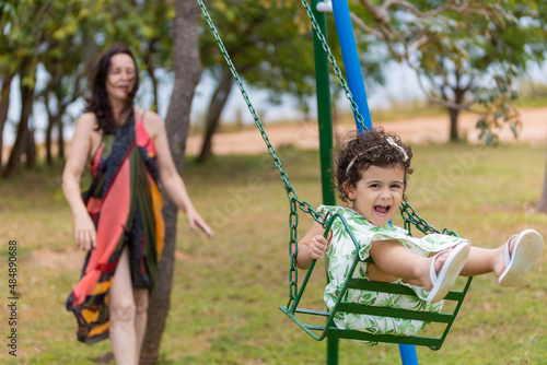 Woman watches child laughing on swing