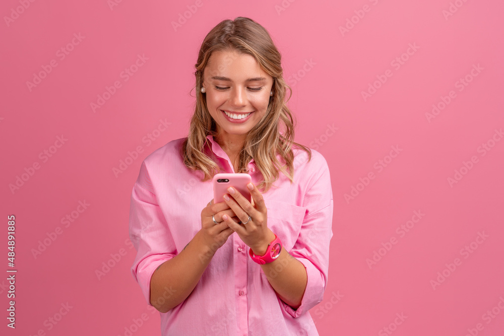 blond pretty woman in pink shirt smiling holding holding using smartphone blond pretty woman in pink shirt smiling holding holding using smartphone