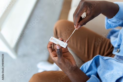 Young African American man taking a Self-swabbing home tests for COVID-19 at home with Antigen kit. Introducing nasal stick to check the infection of Coronavirus. Quarantine  pandemic.