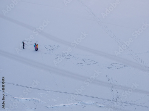 A family with children draw hearts in the snow with their steps.