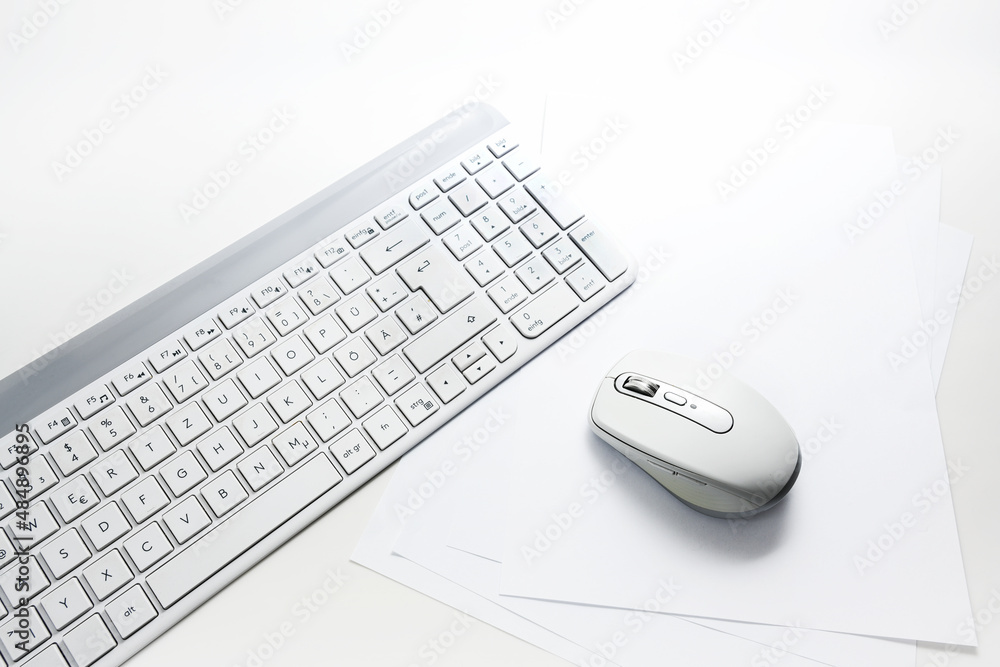 Light gray computer keyboard and mouse on blank paper and a white background with copy space, office concept, selected focus Light gray computer keyboard and mouse on blank paper and a white background with copy space, office concept, selected focus