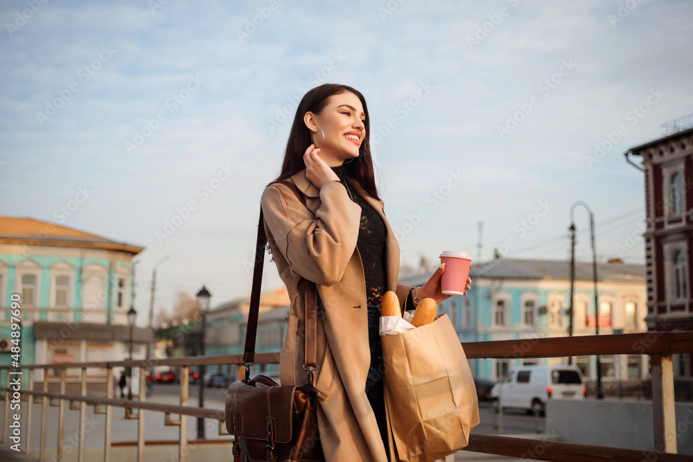 Beautiful woman with coffee to go cup in hewr hand spending time outdoors in the city in spring.