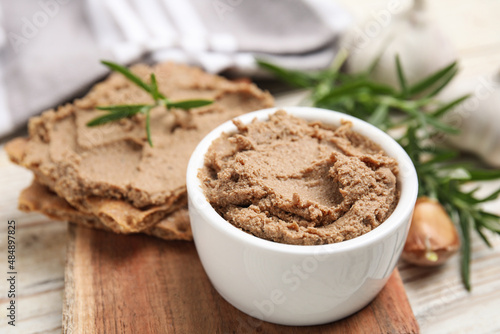 Delicious meat pate, crispy crackers and rosemary on white wooden table, closeup