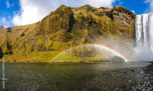 Waterfall with a small rainbow at the foot of a mountain