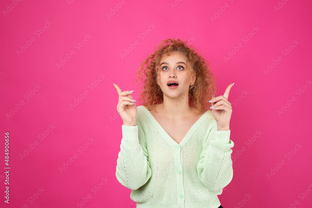 A young girl with curly hair points with a gesture on a studio background. A young girl with curly hair points with a gesture on a studio background.