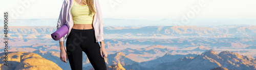 A thin athletic girl takes a break between classes on the background of mountains in the early morning