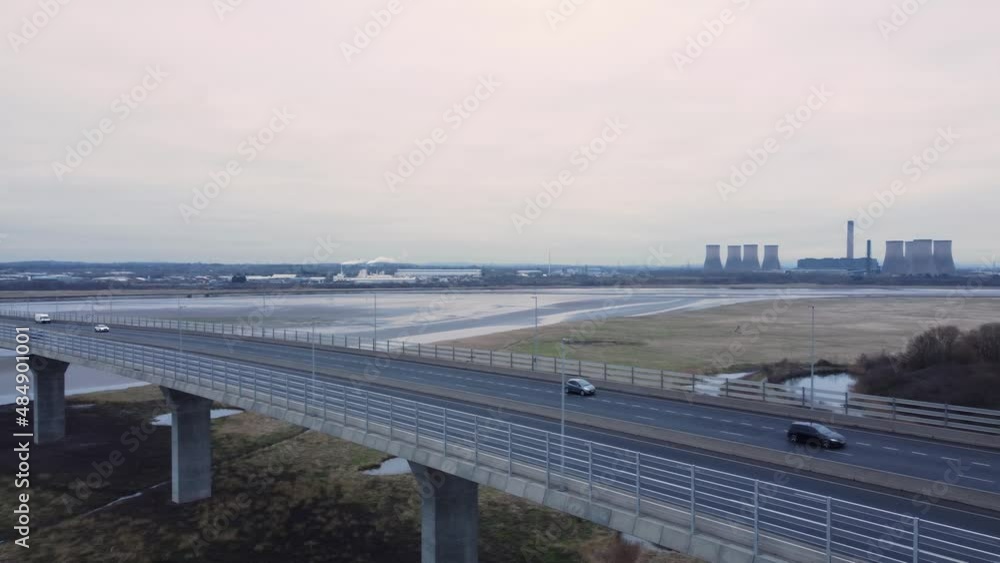Aerial view Mersey Gateway cable stayed toll bridge traffic crossing River Mersey at low tide pan right across highway Aerial view Mersey Gateway cable stayed toll bridge traffic crossing River Mersey at low tide pan right across highway
