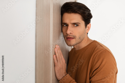 Foto Closeup of young guy listening through the door
