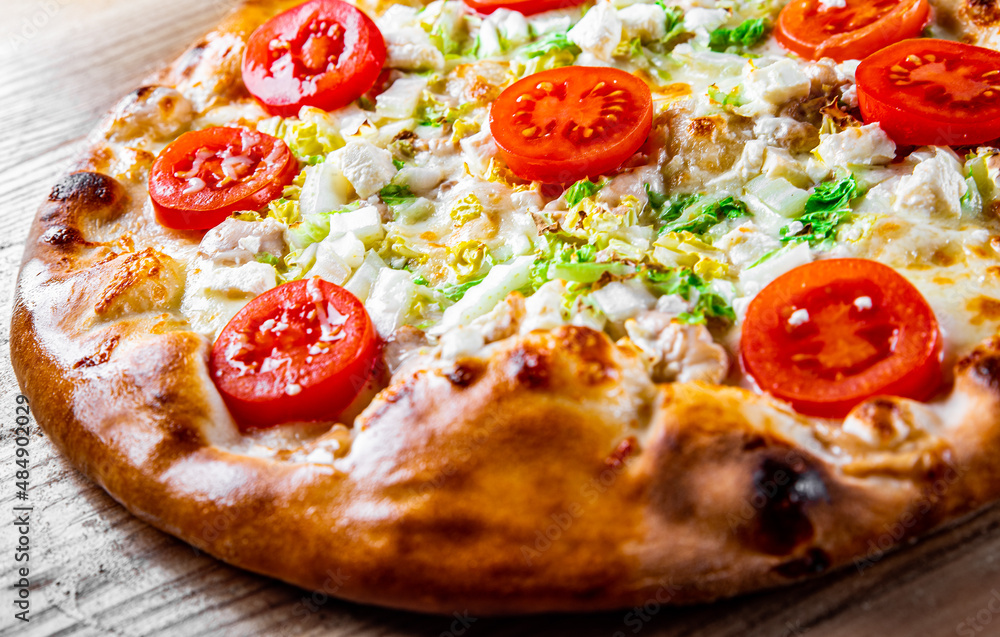 Pizza Caesar with chicken, cheese and tomatoes. Italian pizza on wooden table background Pizza Caesar with chicken, cheese and tomatoes. Italian pizza on wooden table background