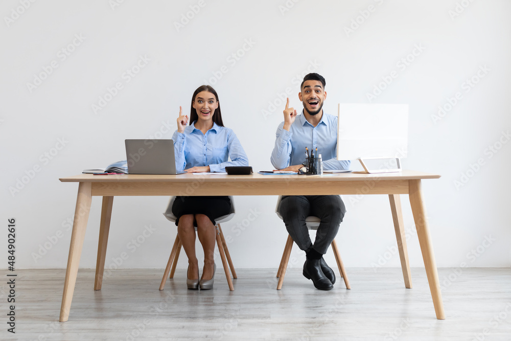 Idea Concept. Excited Colleagues Pointing Fingers Up At Workplace Idea Concept. Excited Colleagues Pointing Fingers Up At Workplace
