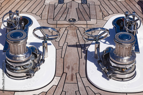 Fototapeta Teak deck of a luxury yacht with stainless steel winches and anchor chain attachment mechanisms
