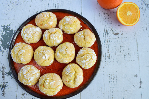 Homemade orange crinkle cookies with powdered sugar icing. Cracked citrus biscuits on white background