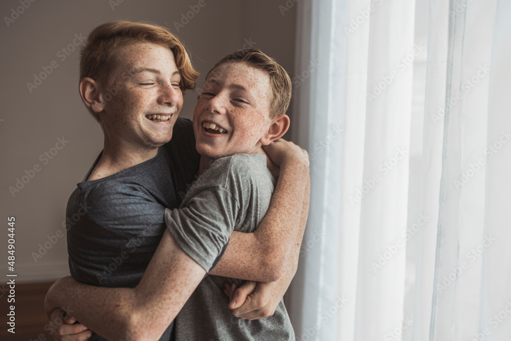 Lifestyle portrait of Redhead teen brothers hugging tightly in studio Lifestyle portrait of Redhead teen brothers hugging tightly in studio