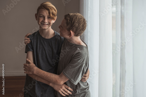 Lifestyle portrait of Redhead teen brothers hugging tightly in studio photo