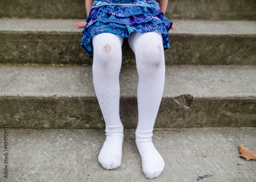 bottom half of shoeless little girl with ripped tights and dirty knees photo