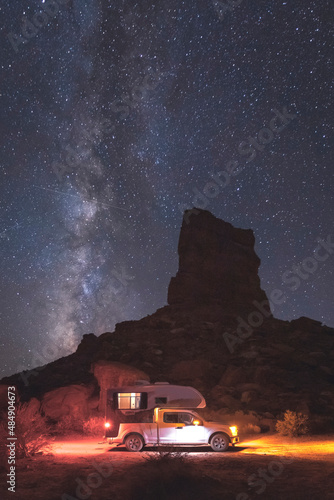 A small pickup RV is on a camping spot under the Milky Way