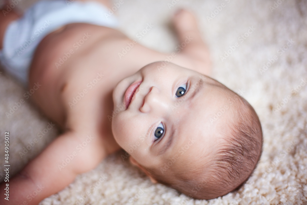Baby boy laying on carpet and looking at the camera. Baby boy laying on carpet and looking at the camera.
