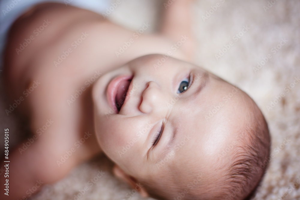 Baby boy laying on carpet and winking at the camera. Baby boy laying on carpet and winking at the camera.