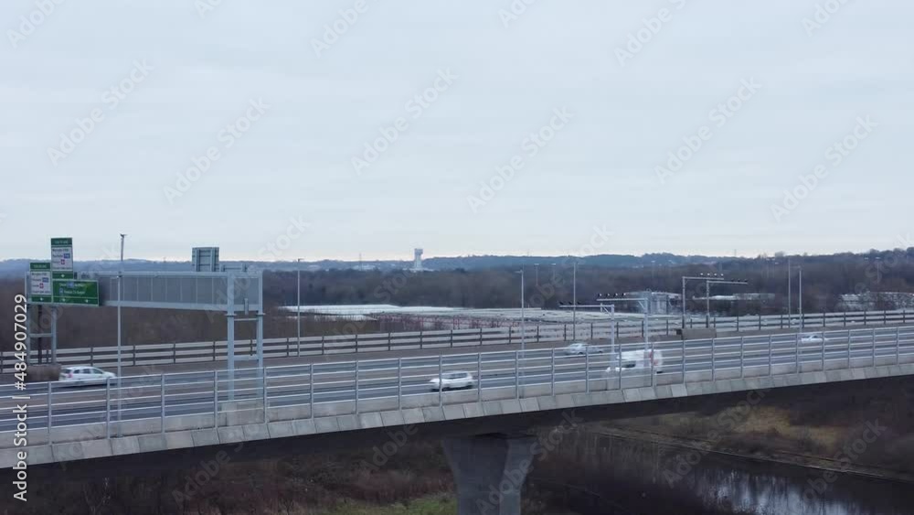 Mersey gateway toll bridge highway traffic driving across river estuary aerial view descending right pan below overpass Mersey gateway toll bridge highway traffic driving across river estuary aerial view descending right pan below overpass