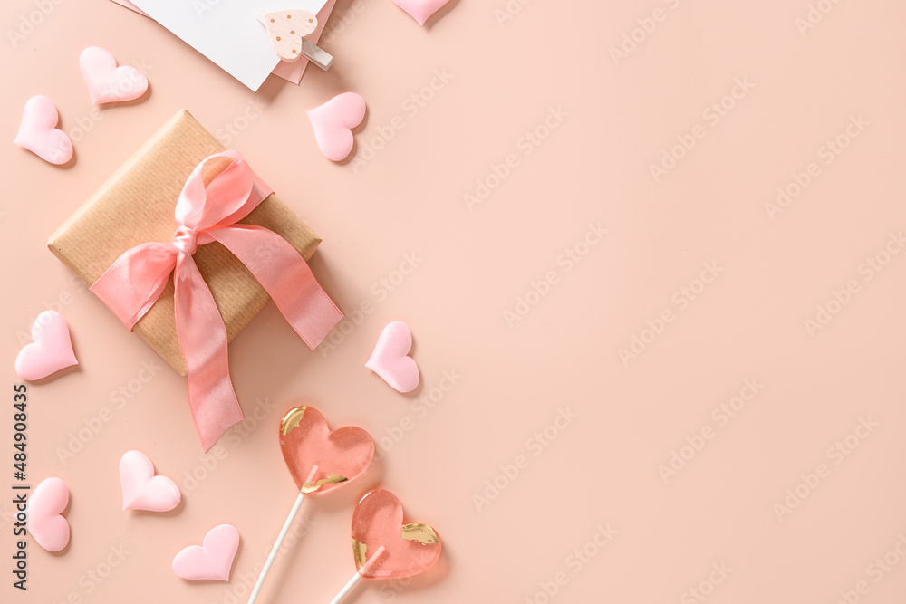 Valentine's day greeting card with gift, love letter,two sweets lollipops and pink hearts on pink background. View from above. Space for text. Flat lay.
