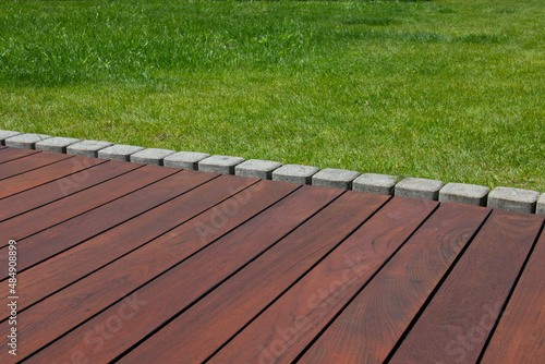 Teak wood deck detail next green grass, natural exotic hardwood lumber flooring