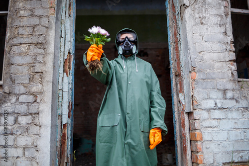 A dosimetrist scientist in protective clothing and a gas mask examines the danger zone. Close-up. flower in hands photo