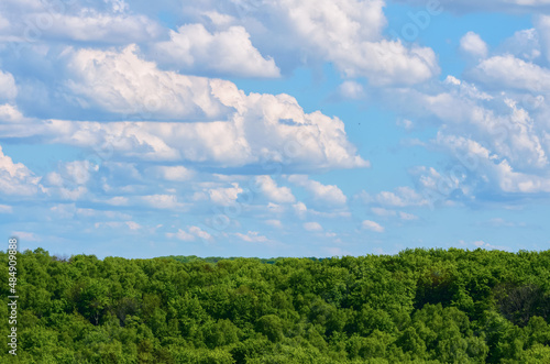Blue sky with clouds over green forest.