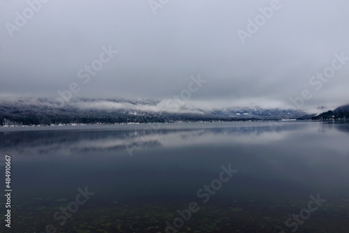 Scenic view of Bohinj lake in Slovenia with low level clouds above the lake and a reflection in the water