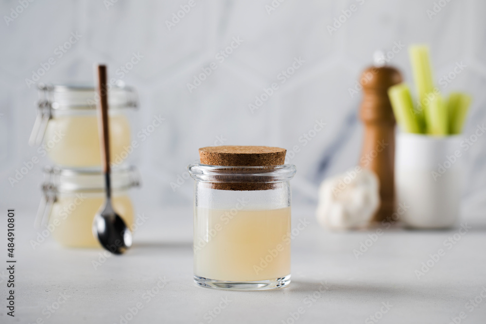 Bone broth soup in glass storage jars with spices and celery on the background. The concept of healthy eating. Bone broth soup in glass storage jars with spices and celery on the background. The concept of healthy eating.