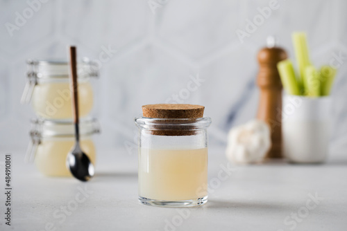 Bone broth soup in glass storage jars with spices and celery on the background. The concept of healthy eating.