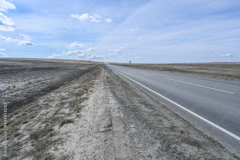 Highway road in the steppes, bushes, grass and cloudy sky. Spring. Highway road in the steppes, bushes, grass and cloudy sky. Spring.
