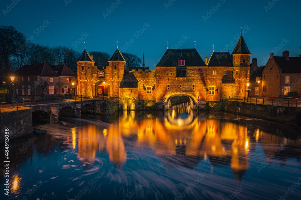 An old medieval gate called the Koppelpoort in Amersfoort with a beautiful reflection in the water during the blue hour