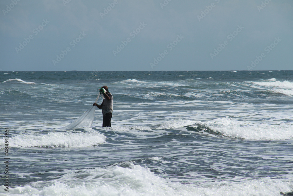 A Balinese fisherman pulling a trawl near the beach in Bali, Indonesia. 