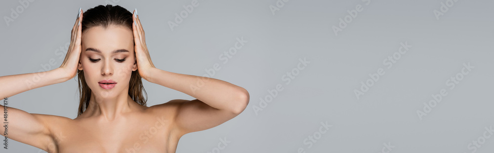 young woman with naked shoulders touching wet hair isolated on grey, banner. young woman with naked shoulders touching wet hair isolated on grey, banner.
