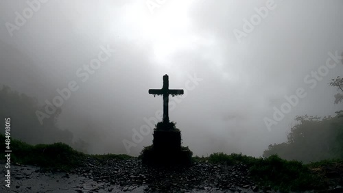 Grave with cross on the edge of foggy Death Road, mysterious place in Bolivia