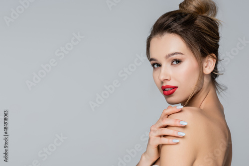 sensual woman with red lips looking at camera isolated on grey.