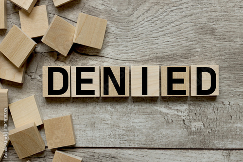 Denied text on wooden blocks on a working wooden table. photo