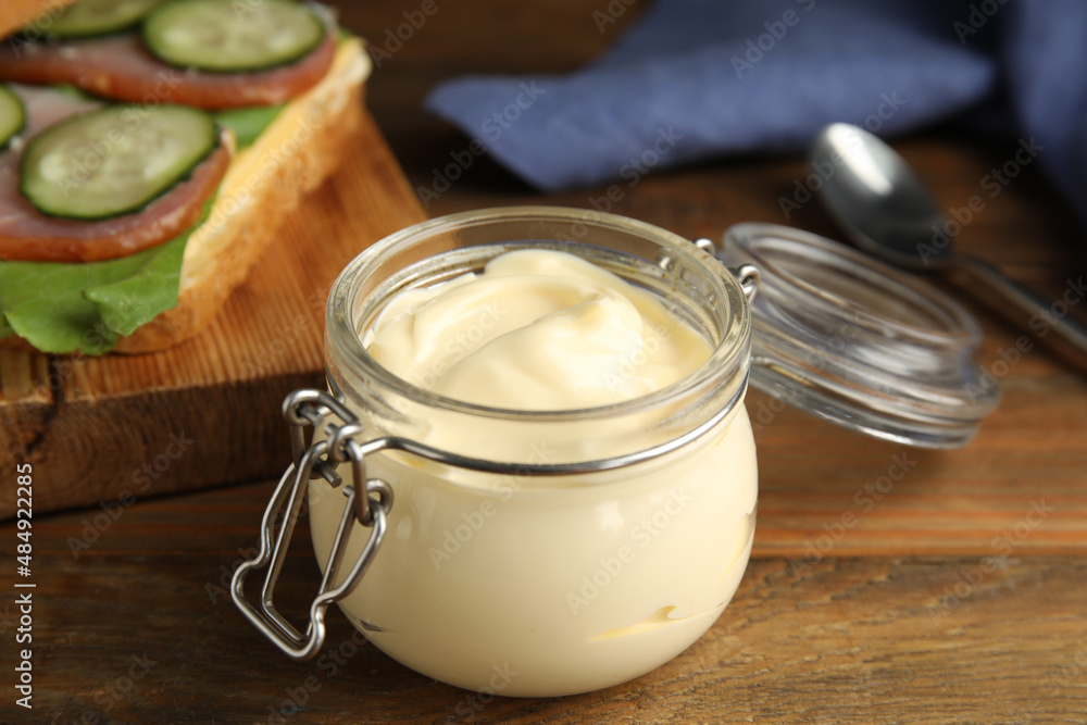 Jar of delicious mayonnaise near fresh sandwich on wooden table Jar of delicious mayonnaise near fresh sandwich on wooden table