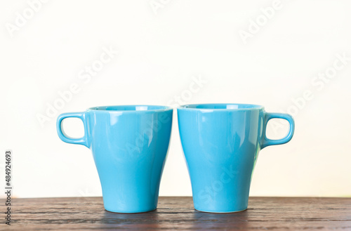 Two aqua blue cups on wood table with isolate white background.