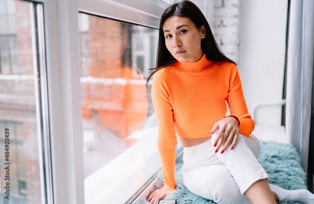 Asian woman sit on windowsill and look at camera Asian woman sit on windowsill and look at camera