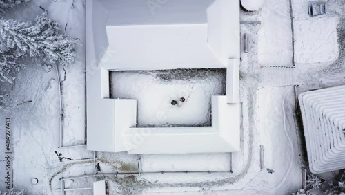 Aerial shot rural landscape in the mountains in winter. Snow-covered houses in the forest from a bird's eye view. Carpathian village in the snow from a height. Flight over the mountains and village. 