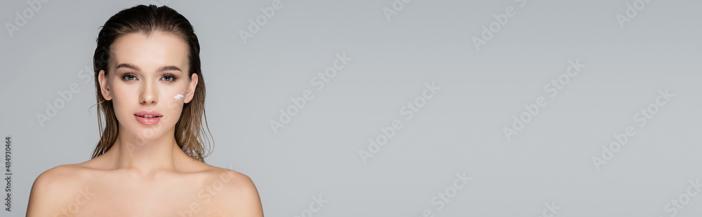 pretty woman with wet hair and cosmetic cream on face looking at camera isolated on grey, banner. pretty woman with wet hair and cosmetic cream on face looking at camera isolated on grey, banner.