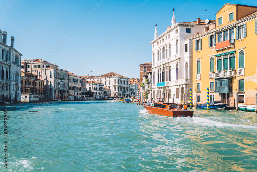 Motorboat floating on clear waters of Grand Canal in romantic Venice during bright summer daytime, landscape with ancient architecture buildings located in historic center of Italian city