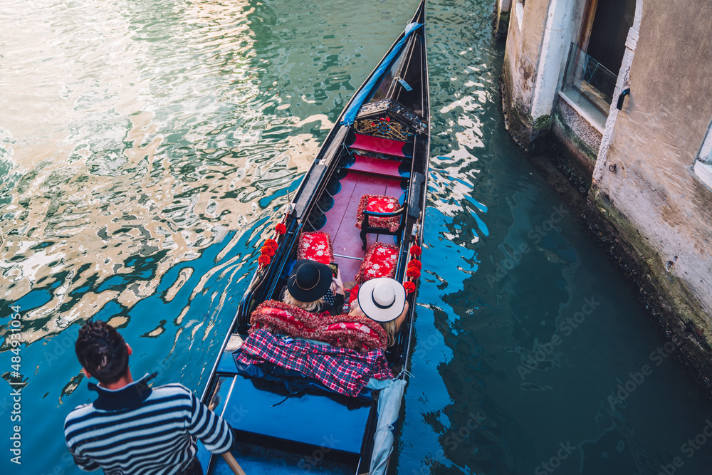 Touristic people as passengers crossing blue water In venice enjoying summer vacations in most romantic city of Europe, unrecognizable female with gondolier enjoying water taxi for have sightseeing