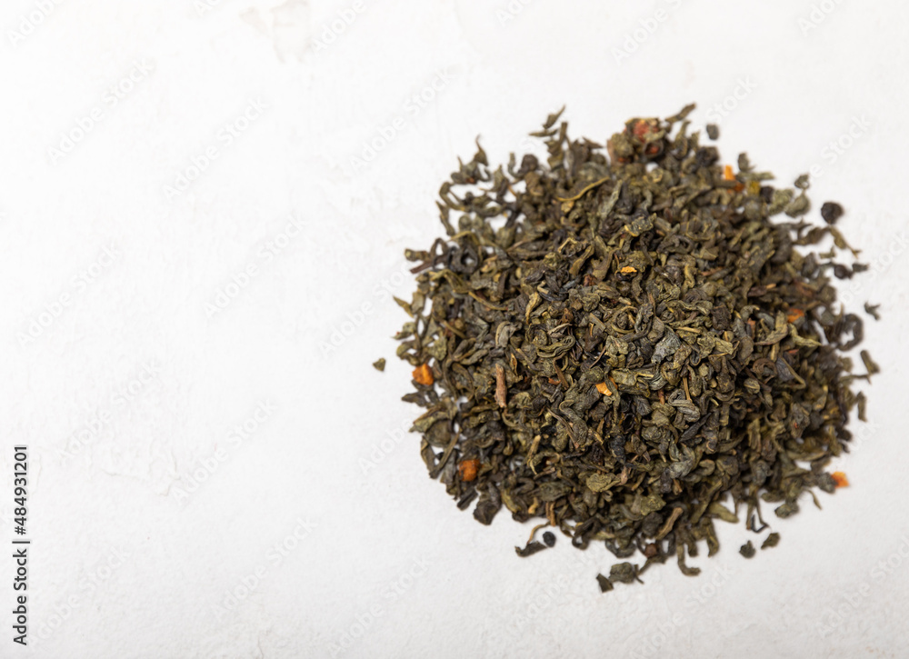 Dried fragrant green tea leaves on a light cement background. Composition with organic, natural green tea. Copy space. Dried fragrant green tea leaves on a light cement background. Composition with organic, natural green tea. Copy space.