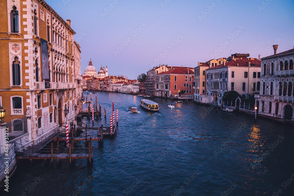 Romantic city in Europe with motorboats floating on Grand Canal during evening time for exploring Venice, Italian architecture and picturesque historic center with ancient landscape for discovering