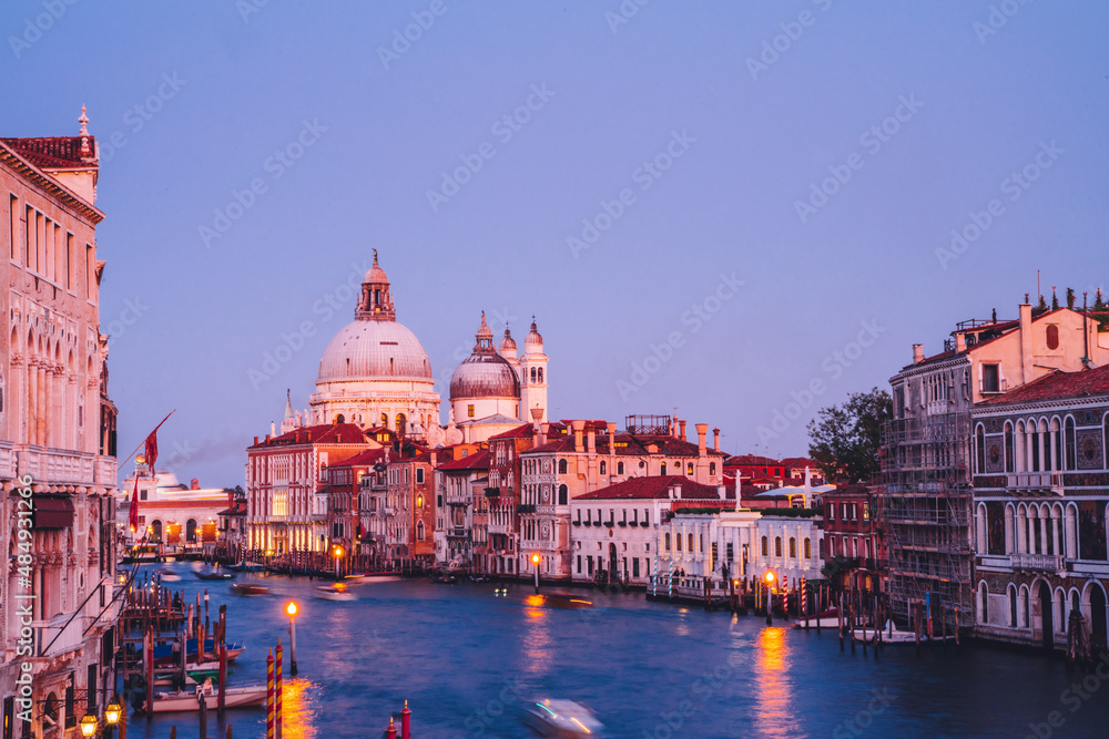 Romantic city in Europe with blurred motorboats floating on Grand Canal during evening time for exploring Vanice, Italian architecture and picturesque historic center with ancient landscape